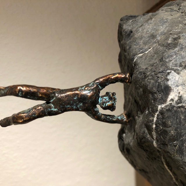 Bronzefigur macht Handstand auf Naturstein